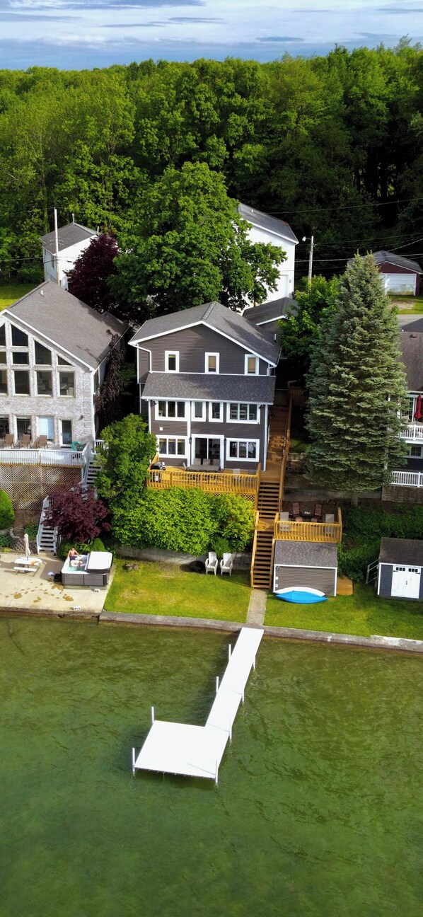 A large house with a deck, a swimming pool, and a boat dock.