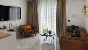 A modern living room with a flat-screen TV, a ceiling fan, a glass coffee table, and two sofas. - Tiger’s Eye, a luxurious apartment situated in the heart of Puerto del Carmen (Puerto del Carmen)