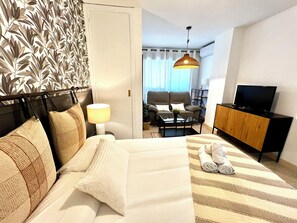 Habitación de hotel con cama, escritorio, silla, televisor y armario.