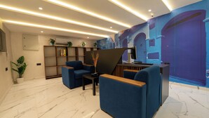 A modern lobby with marble flooring, blue seating, a reception desk, and a mural on the wall. - LUXURY CHAOUEN (Chefchaouen)