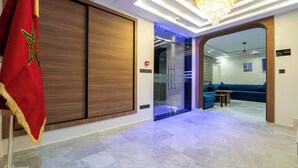 A hotel lobby with a Moroccan flag, a modern chandelier, and a blue sofa area. - LUXURY CHAOUEN (Chefchaouen)