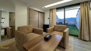 A modern hotel room with a large window, a wooden coffee table, and two beige armchairs. - LUXURY CHAOUEN (Chefchaouen)