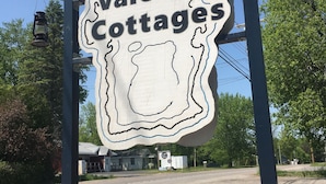 A sign for Valcour Cottages with a sailboat decoration in front. - Lakeside Cottage #305 at Valcour Cottages (Plattsburgh)