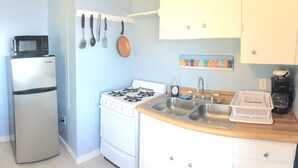 A compact kitchen with a refrigerator, microwave, stove, and sink. - Lakeside Cottage #305 at Valcour Cottages (Plattsburgh)