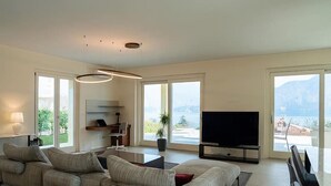 Een moderne woonkamer met een bank, televisie en een balkon met uitzicht.