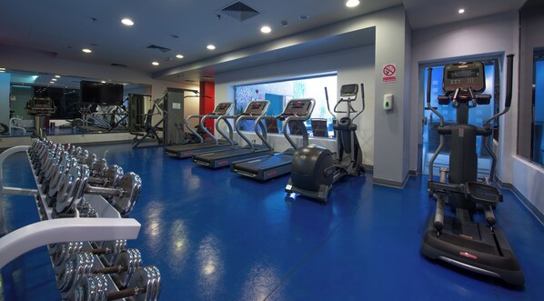 Un gimnasio con cintas de correr, elípticas y máquinas de pesas.