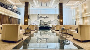 A luxurious lobby with a central reflective floor, elegant chandeliers, and plush seating areas.