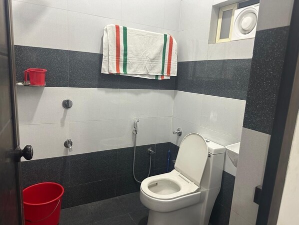 Un baño pequeño con inodoro, ducha y una toalla colgada en la pared.