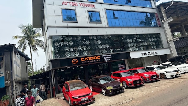 Un edificio con un cartello 'ATTIRI TOWER' e un negozio 'CARDOC AUTOMOTIVE', con auto parcheggiate davanti.