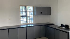 Una cucina moderna con un piano di lavoro nero, mobili bianchi e una finestra con vista sugli edifici.