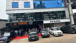 Un edificio che ospita diverse attività commerciali, tra cui 'ATTIRI TOWER', 'CARDOC AUTOMOTIVE' e 'BYB GLOBAL'. Diverse auto sono parcheggiate davanti.