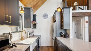 Una cocina moderna con armarios oscuros, una encimera blanca, una cafetera y un reloj en la pared.