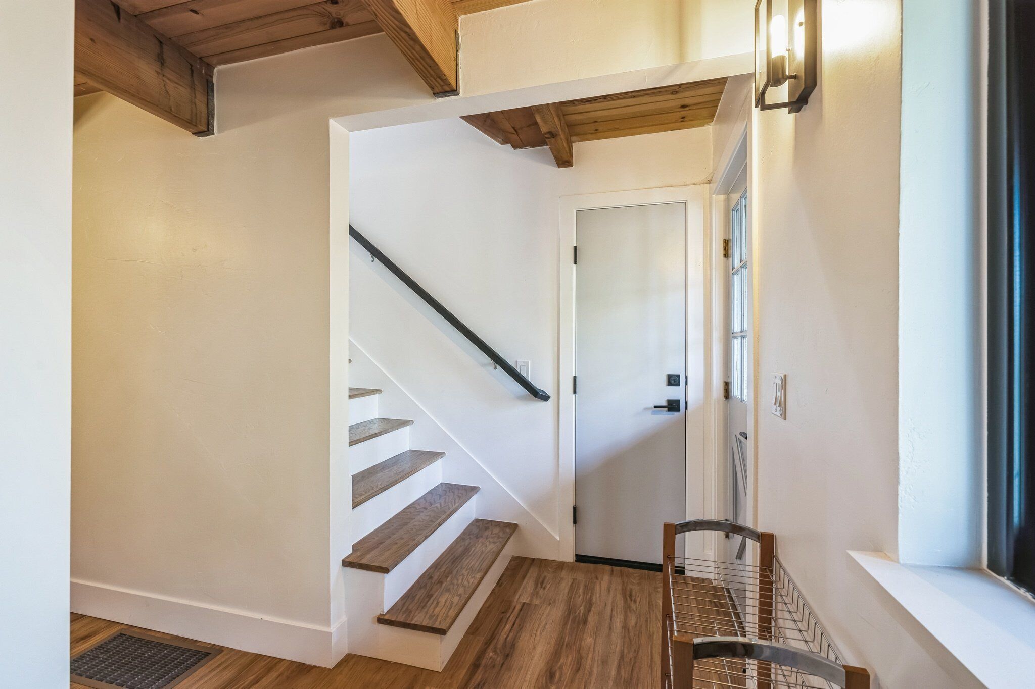 A staircase with wooden steps and a metal handrail, leading to a door with a window.