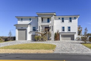 A modern two-story house with a garage, a stone facade, and a well-maintained lawn. - The White House On Flagler Beach - Unit 22 2 Bedroom Home (Flagler Beach)