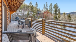 A wooden deck with outdoor seating, overlooking a snowy landscape and a red building in the distance. - Valley View Vistas 3 Bedroom Lodge (Nederland)