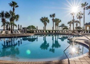 A swimming pool with lounge chairs and palm trees, surrounded by a clear sky. - Beach Club Bristol 101 3 Bedroom Condo (Gulf Shores)