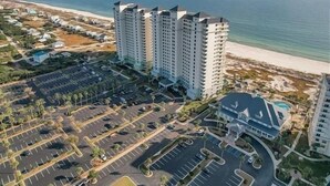 A high-rise hotel with multiple floors, a parking lot, and a beach view. - Beach Club Bristol 101 3 Bedroom Condo (Gulf Shores)