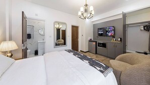 A hotel room with a bed, a desk, a mirror, a TV, a wardrobe, and a bathroom.