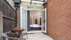 A small patio with a table and chairs, a wooden fence, and a brick wall.
