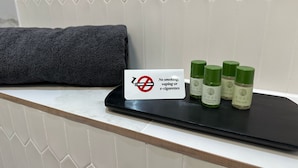 A sign prohibiting smoking, vaping, or e-cigarettes, and three bottles of Eden body wash on a black tray.