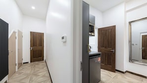 A modern kitchen with a built-in microwave, a refrigerator, and wooden doors.
