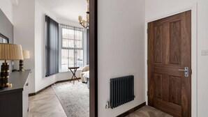 A modern hallway with a wooden door, a radiator, and a window with curtains.