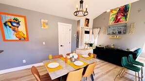 Un coin repas avec une table dressée pour quatre personnes, un lustre et des œuvres d’art accrochées aux murs.