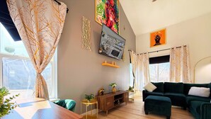 Un salon moderne avec une table basse en bois, un canapé vert et un téléviseur fixé au mur.