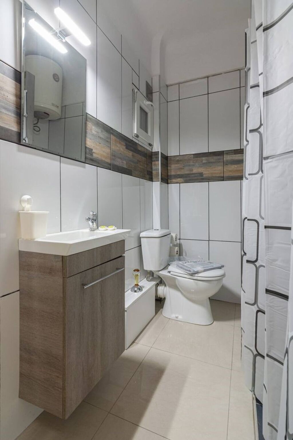 A bathroom with a toilet, sink, and mirror.