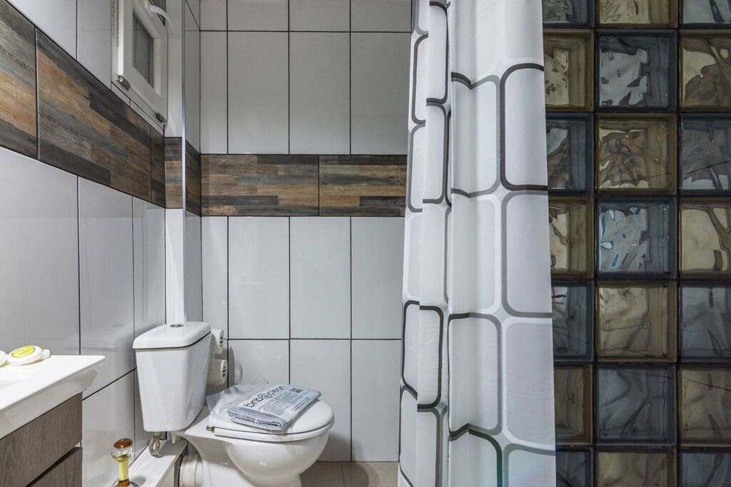 Ein modernes Badezimmer mit Toilette, Waschbecken und einer Duschvorhang mit geometrischem Muster.