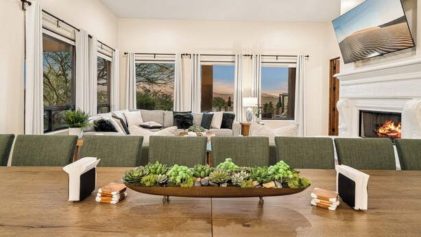 A spacious living room with a fireplace, a large window with curtains, a dining table with chairs, and a sofa with cushions. - Scottsdale Rose Sleeps 40 Pool Pickleball Rooftop (Scottsdale)