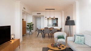 Un salon moderne comprenant un téléviseur, un canapé, une table basse et un coin repas.