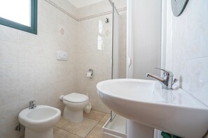 A bathroom with a bidet, toilet, and sink.