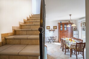 A staircase leading to a dining area with a table set for two, wooden cabinets, and a refrigerator.