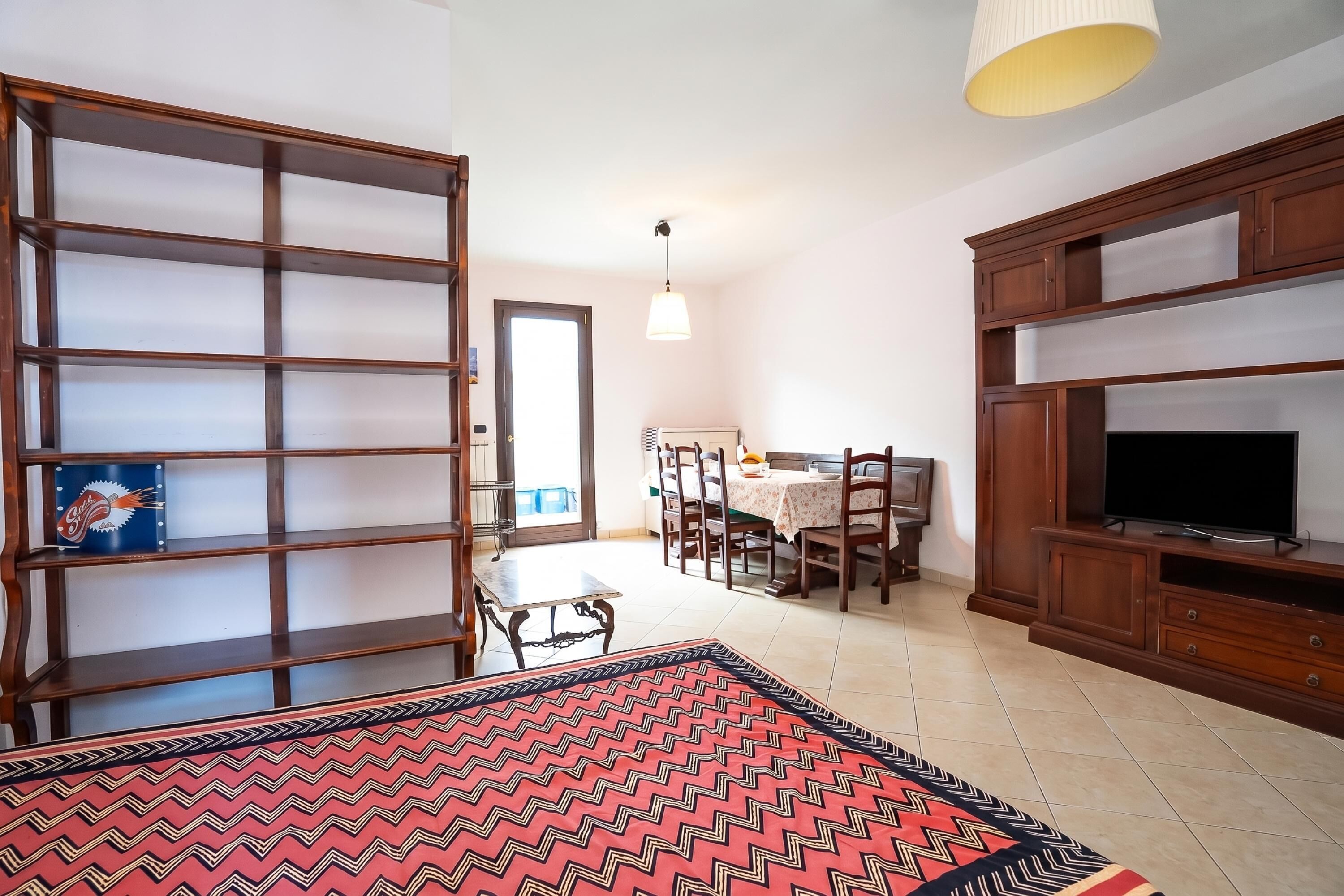A compact living space with a dining area, a television, and a bookshelf.