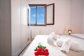 Une chambre d’hôtel avec un lit, une table de chevet avec une lampe, une fenêtre et un radiateur.