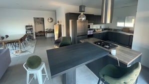 Una cocina moderna con una isla central, electrodomésticos de acero inoxidable y un comedor con mesa y sillas.
