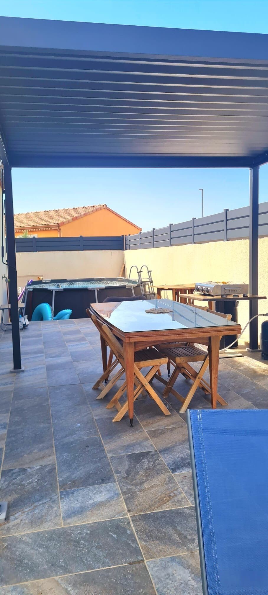 An outdoor patio area with a covered seating area, a table, and a grill station.