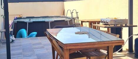 An outdoor patio area with a covered seating area, a table, and a grill station.