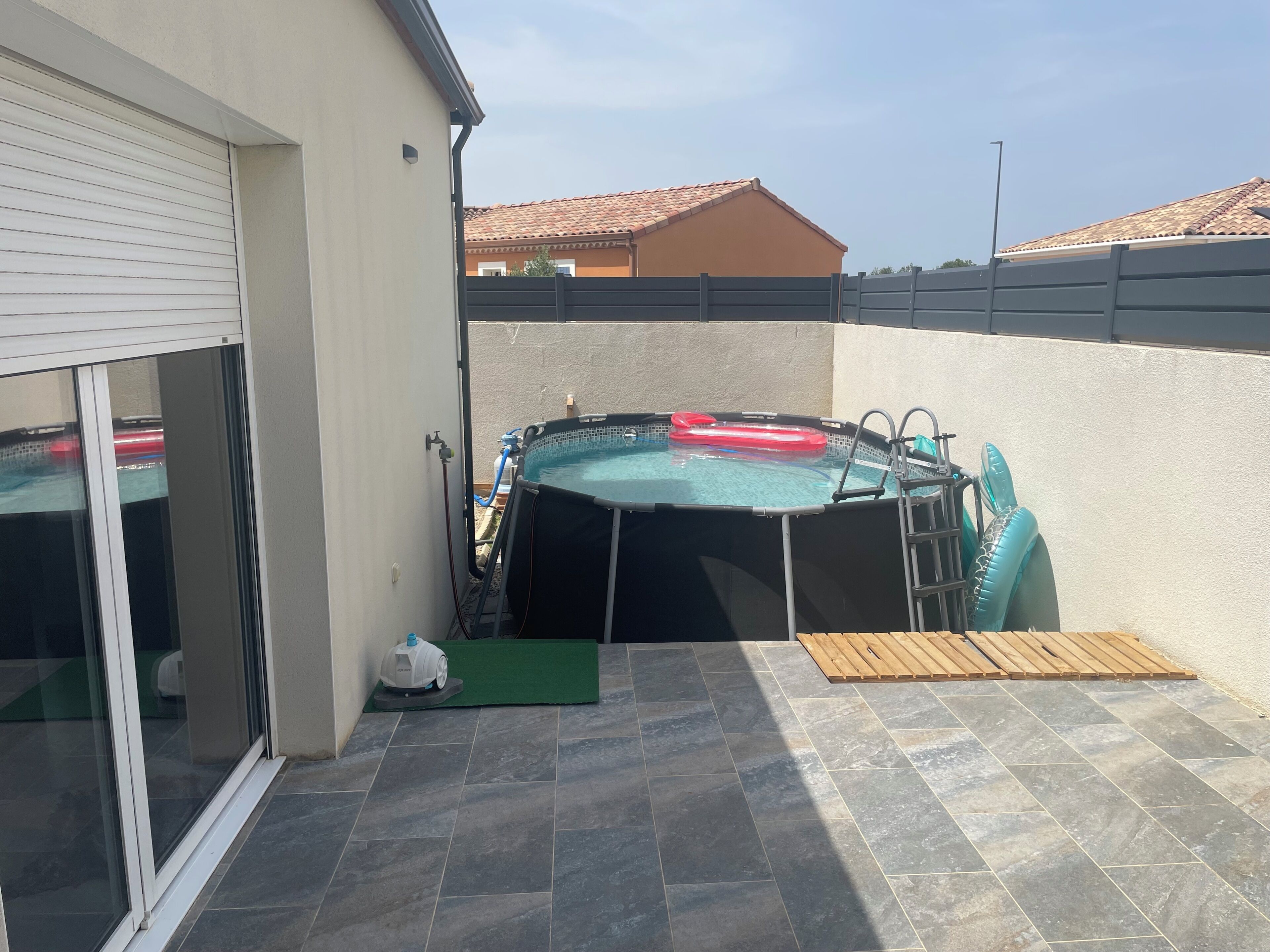 En baghave med en swimmingpool, vandvarmer og en træterrasse.