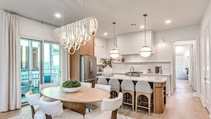 A modern kitchen with a central island, pendant lights, and a view to the outside. - Carlton Landing-Shingle Ready to Mingle (Carlton Landing)