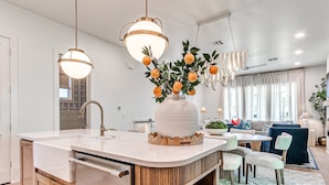 A modern kitchen with a central island, wooden cabinets, and pendant lighting. - Carlton Landing-Shingle Ready to Mingle (Carlton Landing)