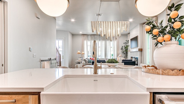 A modern kitchen with a large white sink, wooden cabinets, and a chandelier. - Carlton Landing-Shingle Ready to Mingle (Carlton Landing)
