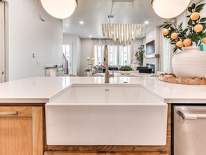 Eine moderne Küche mit einem großen, weißen Spülbecken, Holzschränken und einer Kristallleuchter.