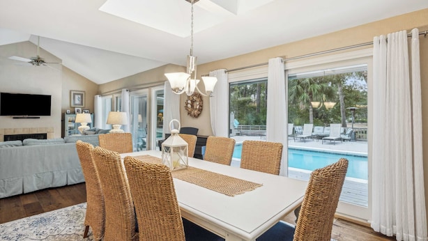Un comedor con sillas de mimbre, una mesa blanca y vista a una piscina.