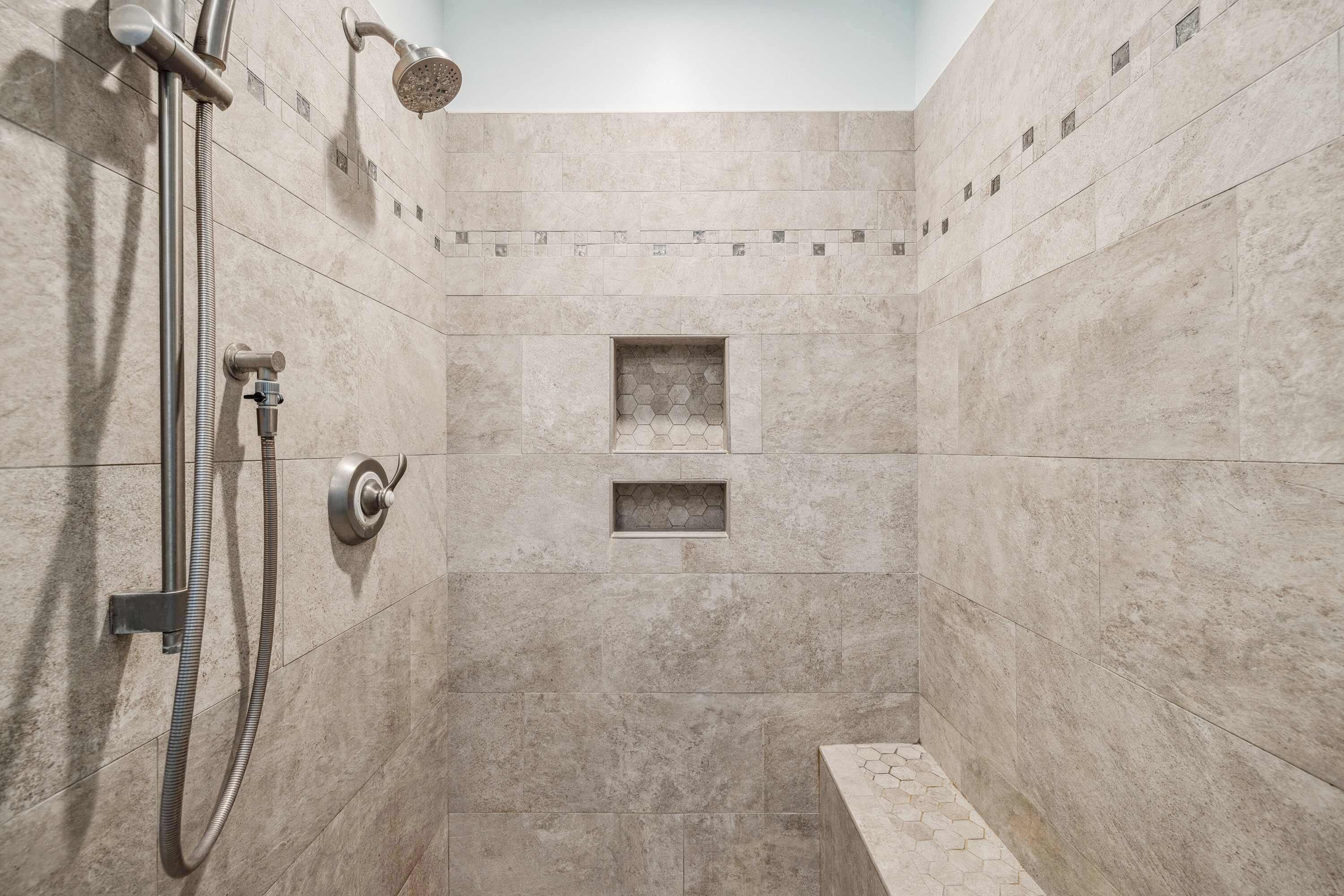 A shower with a handheld showerhead and a wall-mounted faucet.