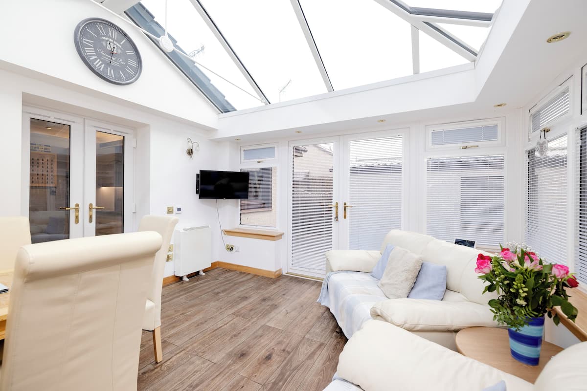A modern living room with a skylight, white furniture, and a clock on the wall.