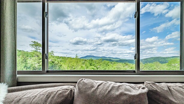 A window with a view of green hills and a partly cloudy sky. - Two bedroom North Peak Condo (Newry)