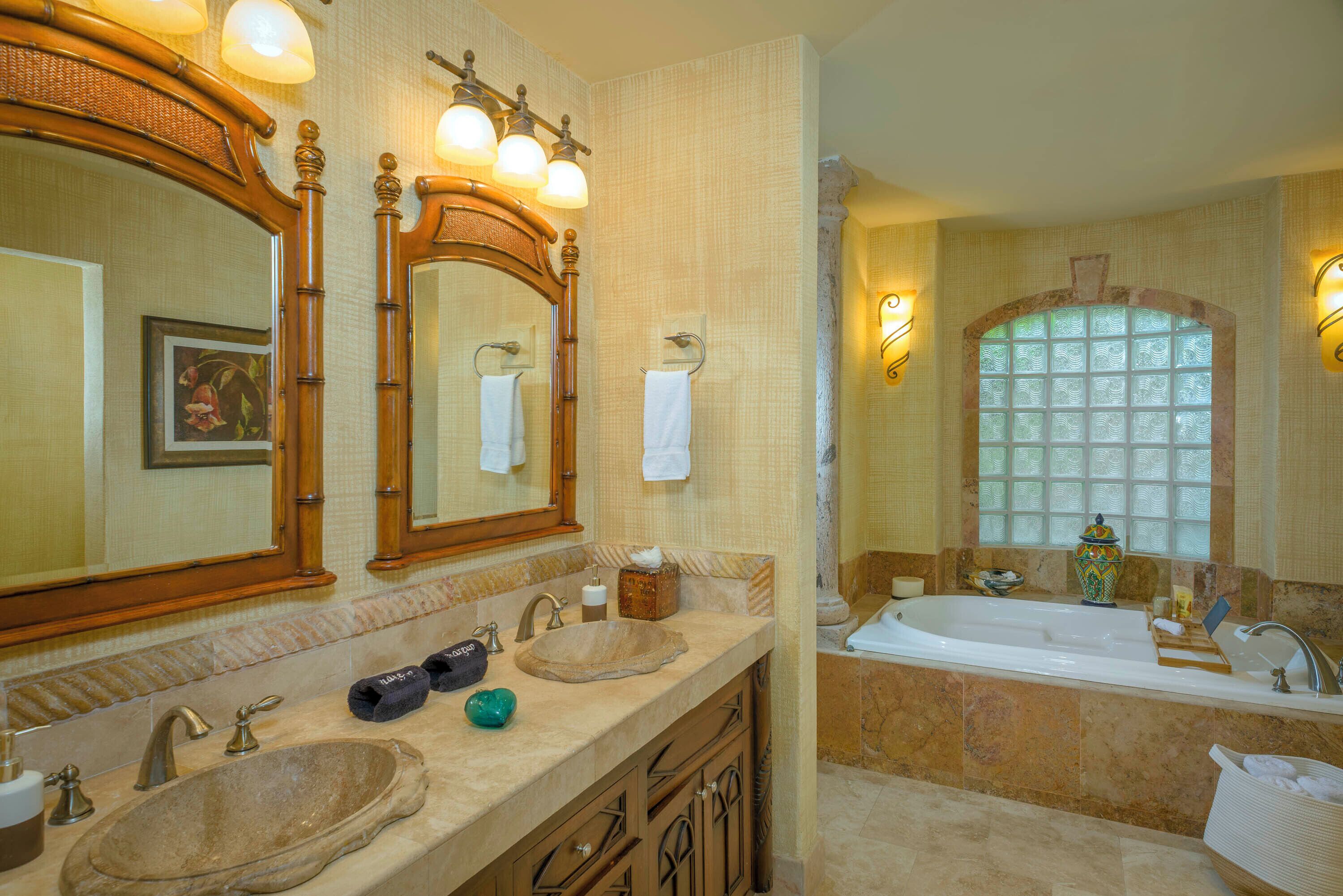 Une salle de bain avec deux lavabos, un grand miroir et une baignoire.
