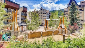 A hotel courtyard with a playground, outdoor seating, and a mountain backdrop. - Rooftop Hot tub, next to Vail Mtn   Studio (Vail)